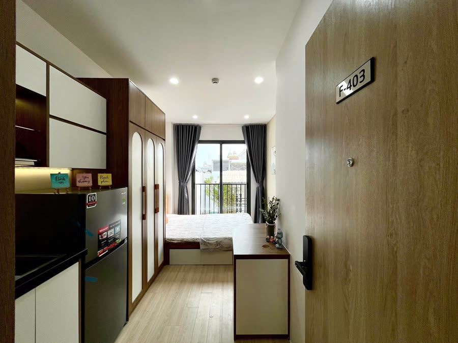 Căn hộ dịch vụ Felix House 9 nhìn từ cửa vào: bếp, tủ, giường, ban công